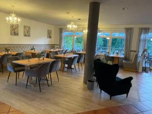 un restaurante con mesas y sillas de madera y ventanas en Hotel und Restaurant zum bunten Hirsch en Mirow