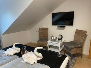 a living room with swans on the bed and a tv at Hotel und Restaurant zum bunten Hirsch in Mirow