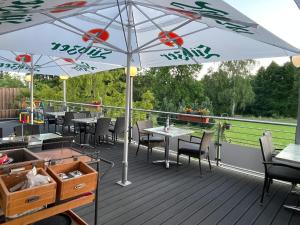 eine Terrasse mit Tischen, Stühlen und einem Sonnenschirm in der Unterkunft Hotel und Restaurant zum bunten Hirsch in Mirow