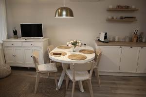 a kitchen with a white table with chairs and a tv at Apartamenty nad Zalewem 213 in Serock