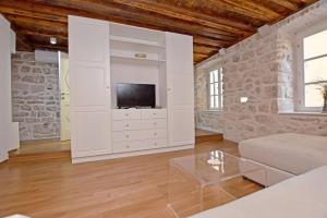 a living room with a large white cabinet with a tv at Pearl in the Heart of Old Town on Belavista Square in Herceg Novi in Herceg-Novi
