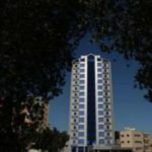 a tall building in front of a blue sky at Roomi Suites Hotel in Kuwait