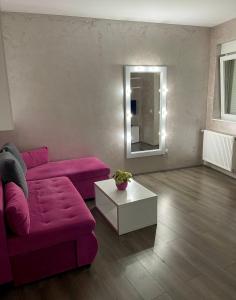 La Apartamento في ياغودينا: غرفة معيشة مع أريكة وردية وطاولة بيضاء
