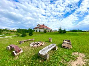 a field with a fire pit in front of a house at Miła Dolina in Miłakowo