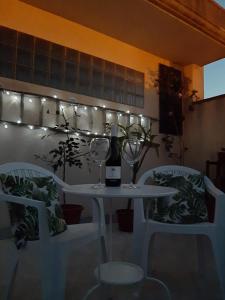 un tavolo bianco con una bottiglia di vino e due sedie di Rosso di Sera Loft a Menfi