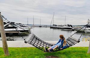 a young girl sitting on a hammock near a marina at Apartamenty Turystyczne WillkasSen in Giżycko