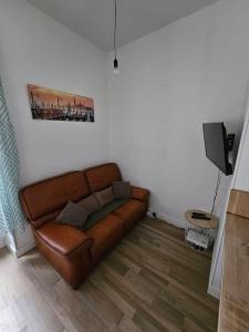 um sofá de couro castanho numa sala de estar em Le Verdun - centre Pau - calme em Pau