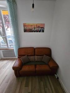 um sofá de couro castanho sentado numa sala de estar em Le Verdun - centre Pau - calme em Pau
