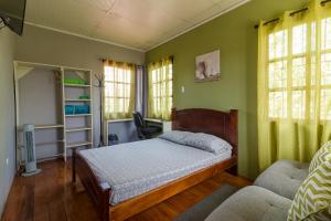 a bedroom with a bed and a chair and windows at Delcafetalcr in San José