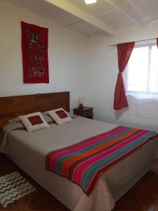 - une chambre avec un lit et une couverture colorée dans l'établissement Casa Sutar Los Pimientos, à San Pedro de Atacama