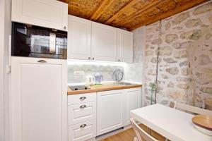 a kitchen with white cabinets and a stone wall at Pearl in the Heart of Old Town on Belavista Square in Herceg Novi in Herceg-Novi