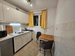 Una cocina con gabinetes blancos y una mesa de madera. en Przytulny Apartament w centrum, en Szczecin