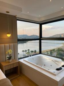 a large bathroom with a large window with a bath tub at Vista do Lago Hotel in Capitólio