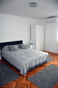 a white bedroom with a bed and a rug at Apartman DJURDJEVAK in Vršac