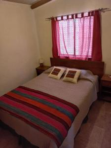 a bedroom with a bed with a red window at Casa Sutar Las Higueras in San Pedro de Atacama