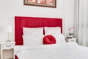 ein weißes Bett mit einem roten Kopfteil und weißen Kissen in der Unterkunft Dodi RED Apartament in Arad