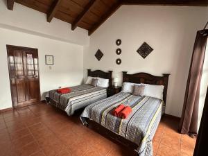 um quarto com 2 camas e almofadas vermelhas em Casa Los Habitantes Antigua Guatemala em Antigua Guatemala