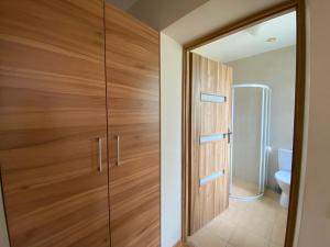 a wooden door in a bathroom with a toilet at Apartamentai su jaukiu kiemu- SOLEY APARTAMENTAI No1 in Palanga