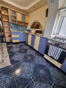 a kitchen with blue and yellow cabinets and tile floors at Emily Residence in Curtea de Argeş