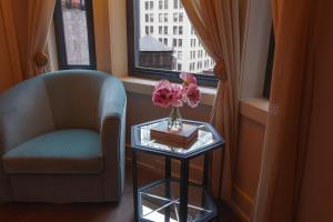 a chair and a table with a vase of flowers on it at The Evelyn NoMad in New York