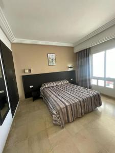 a bedroom with a bed and a large window at Andalucia Bizerte plage et piscine in Bizerte