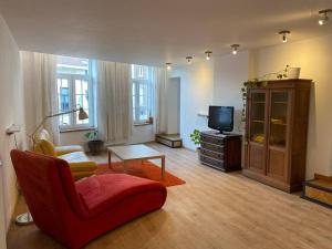 un soggiorno con sedia rossa e TV di The Sugar Cube a Tienen