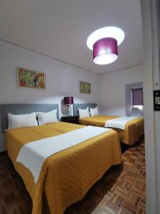 Zimmer mit 2 Betten mit gelber und weißer Bettwäsche in der Unterkunft Ricky House Big Waves in Nazaré