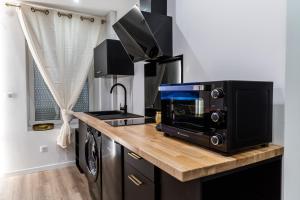 uma cozinha com uma bancada com um micro-ondas e um fogão em Le Vulcano : duplex lounge ! em Vesoul