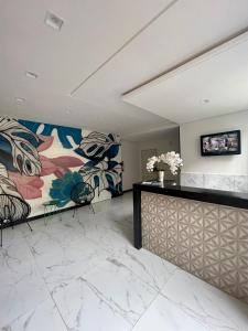 a lobby with a marble counter and a painting on the wall at Mundial Flat in Viçosa