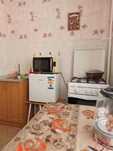 eine Küche mit einer Mikrowelle, einem Herd und einem Tisch in der Unterkunft Уютная квартира с удобным расположением in Līsakovsk