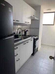 een keuken met witte kasten en een zwarte koelkast bij Hermoso departamento de 2 dormitorios con una vista maravillosa in Valparaíso