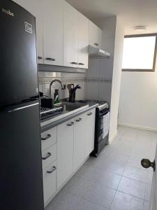 cocina con armarios blancos y nevera negra en Hermoso departamento de 2 dormitorios con una vista maravillosa en Valparaíso