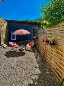 un patio con 2 sillas y una mesa con sombrilla en Petite maison au calme avec jardin clôturé les animaux bienvenue en Mollau