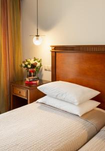 a bed with a wooden headboard and a vase of flowers on a table at Hotel El Greco in Thessaloniki