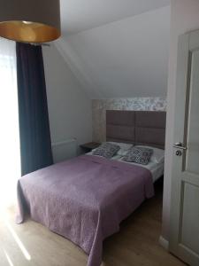 een slaapkamer met een bed met een paarse deken en kussens bij A-ura Pokoje goscinne in Mikołajki
