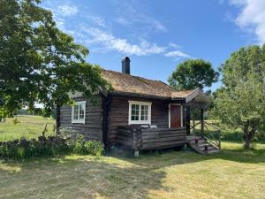 una antigua casa de madera con un porche en un campo en Backgårdens Timmerstuga, en Falkoping