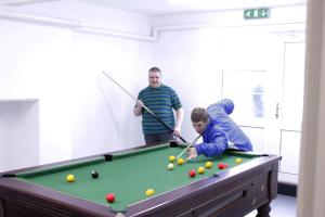 un groupe de trois hommes jouant au billard dans l'établissement Gwesty Seren Hotel, à Blaenau Ffestiniog