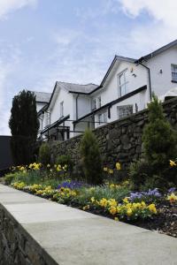 a house with a retaining wall and a garden with flowers at Gwesty Seren Hotel in Blaenau-Ffestiniog