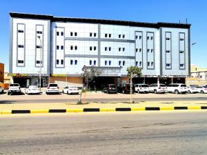 a large white building with cars parked in a parking lot at شذا الشمال للشقق المخدومة in Sakakah