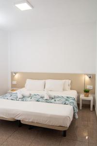 Una cama grande con sábanas blancas y almohadas. en Le Petit Paradis, en Playa de las Américas