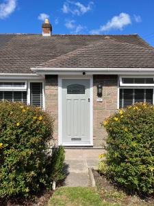 uma casa com uma porta branca e dois arbustos em Idyllic bungalow, ideal location in West Lancashire em Burscough