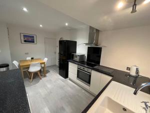 a kitchen with a black refrigerator and a table at Idyllic bungalow, ideal location in West Lancashire in Burscough