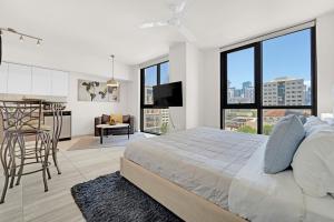 マイアミにあるDevereaux Miami Luxury One-Bedroom and Studiosの白いベッドルーム(大型ベッド1台付)、キッチンが備わります。