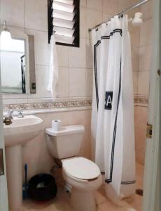 a bathroom with a toilet and a sink and a shower curtain at Casa los Arcos Oaxaca in Oaxaca City