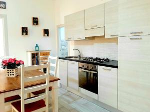 una cucina con armadi bianchi e piano cottura di Dream Home Alghero ad Alghero