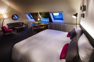 a bedroom with a large white bed and a desk at pentahotel Leuven in Leuven