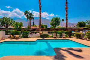 a swimming pool with palm trees and mountains in the background at Mesquite Chic Retreat Permit# 3160 in Palm Springs