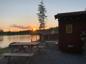 a picnic table in front of a cabin with the sunset at Stuga med sjöläge in Kopparberg