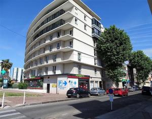a large white building with cars parked in front of it at Charmant T2 Climatisé proche du centre et des commerces - Gare à 15 minutes in Toulon +3 photos