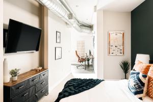 a bedroom with a bed and a tv on a wall at Modern Industrial Loft - Center of RiNo Art District in Denver